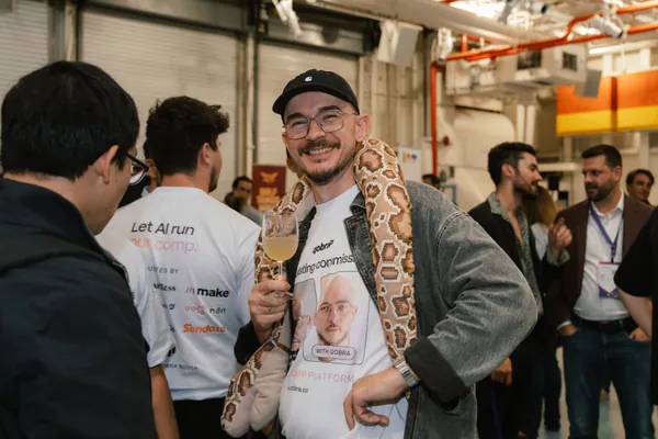 A grinning guest wears a python around his shoulders, drink in hand.
